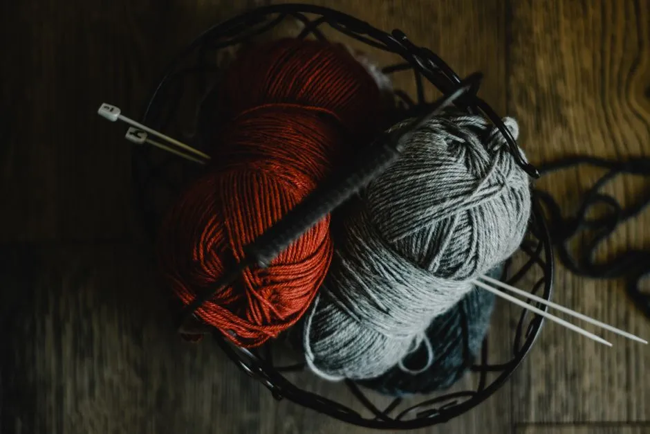Knitting needles resting on balls of yarn, illustrative photo