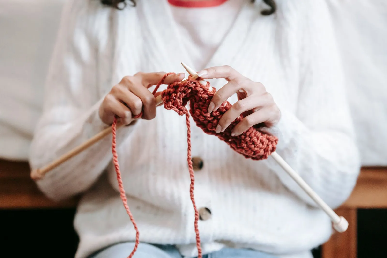 Close-up of hands knitting with needles and pale yarn, illustrative photo